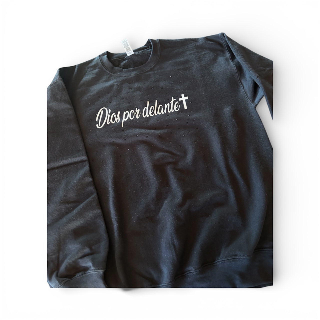 Black sweatshirt with white text 'Dios por delante' with black scattered rhinestones around the text, on a white background