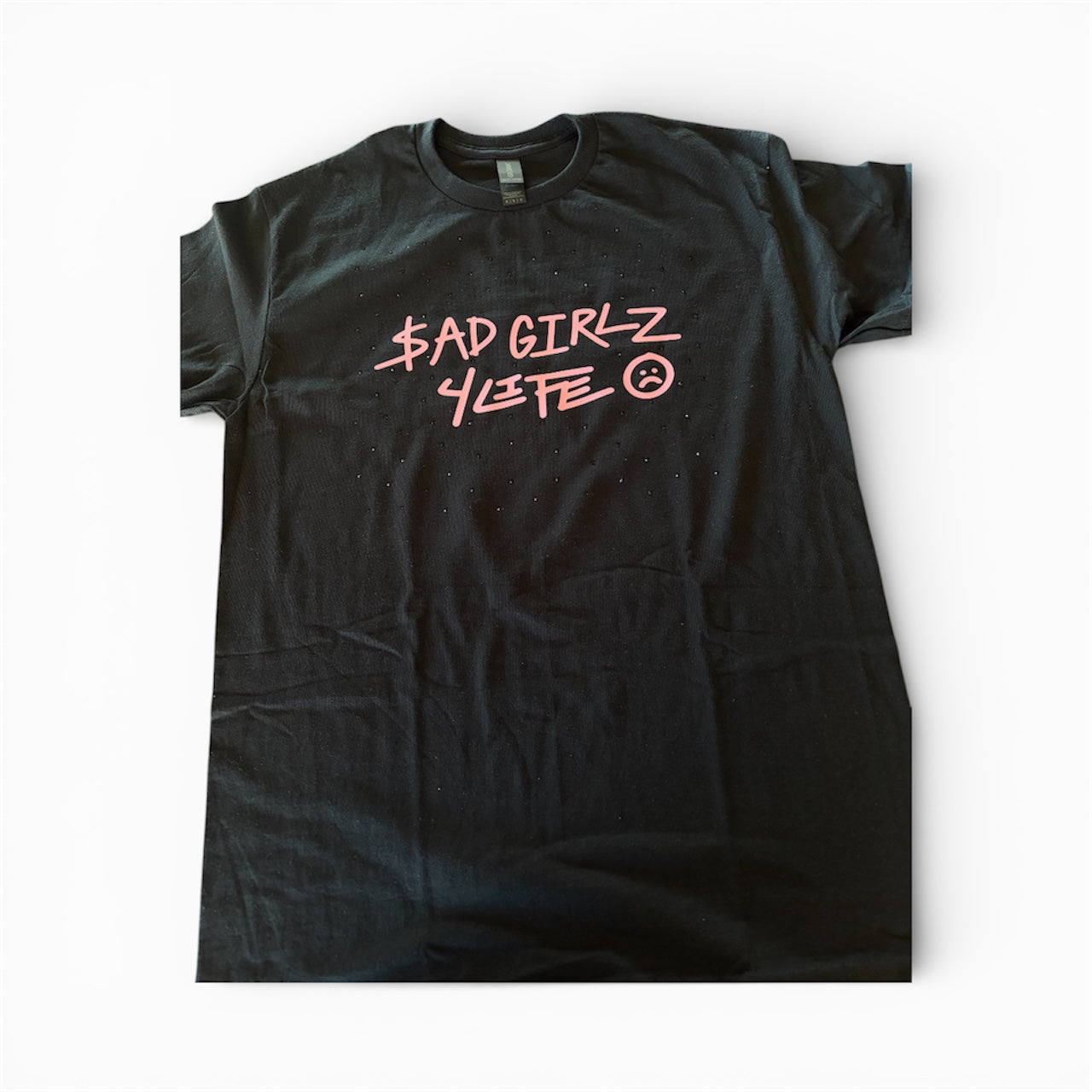 Black t-shirt with pink text, and black scattered rhinestones around the text on a white background