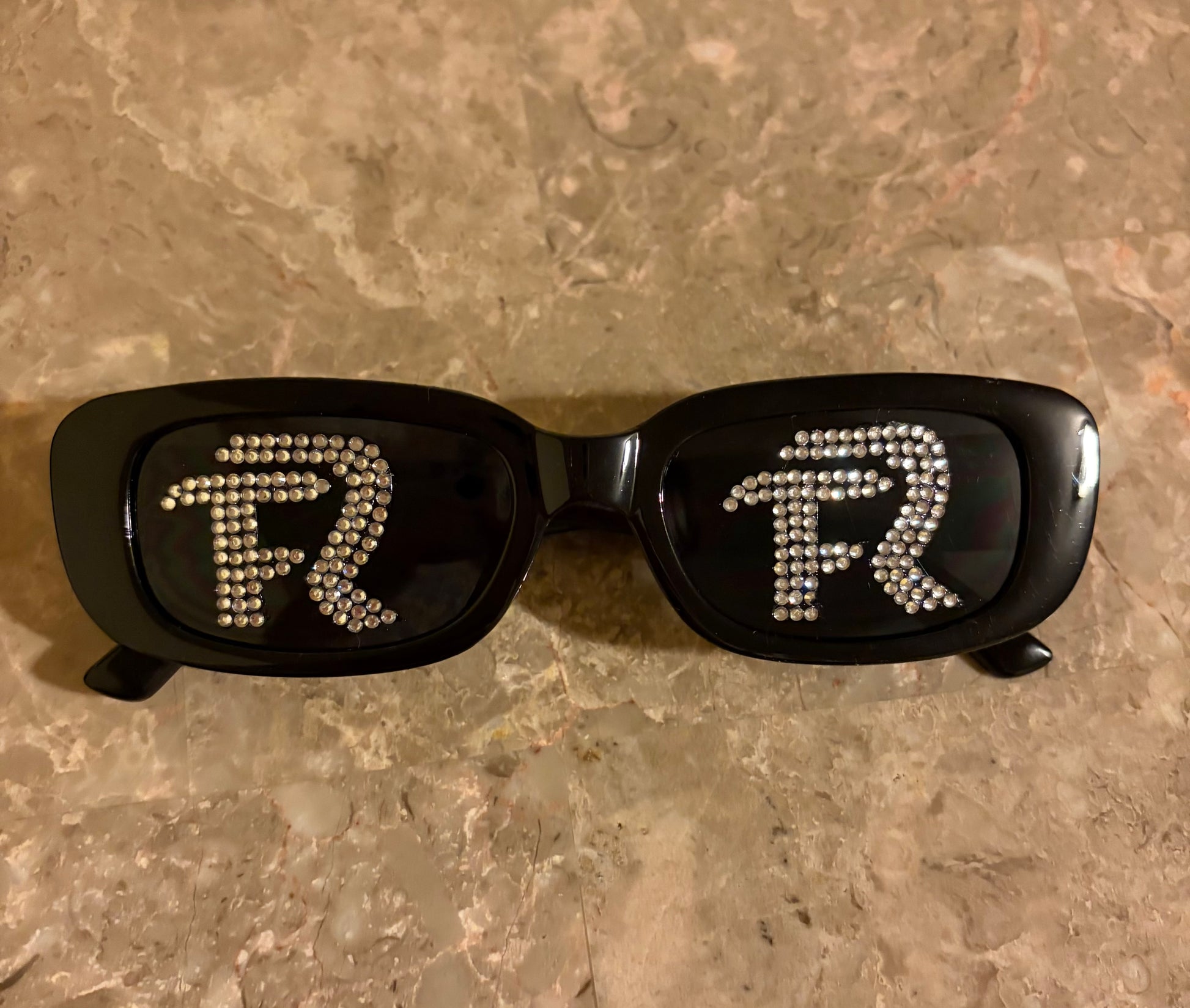 Black sunglasses with decorative elements on a textured surface