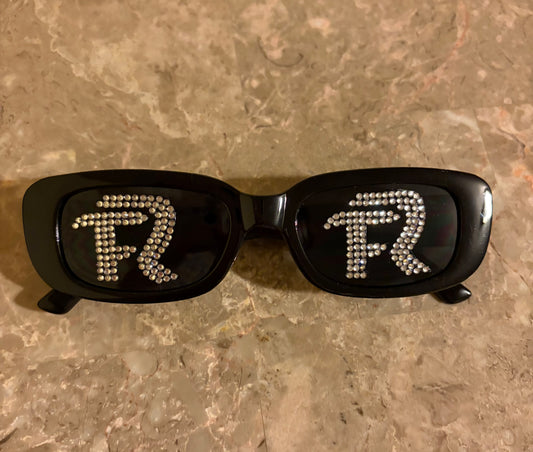 Black sunglasses with decorative elements on a textured surface